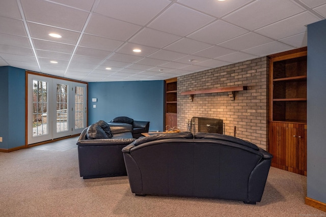 carpeted living room featuring built in shelves, a drop ceiling, and a fireplace