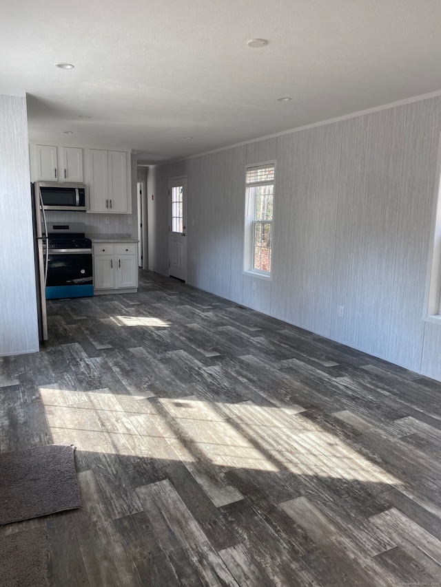 kitchen featuring white cabinets, ornamental molding, stainless steel appliances, and dark wood-type flooring