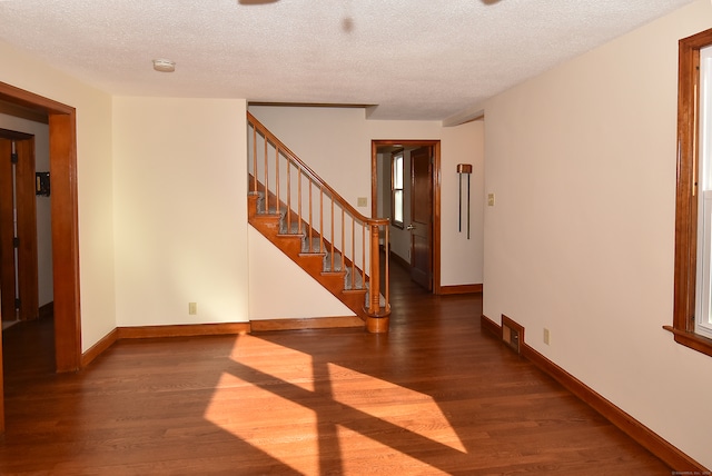 unfurnished room with a textured ceiling and dark wood-type flooring