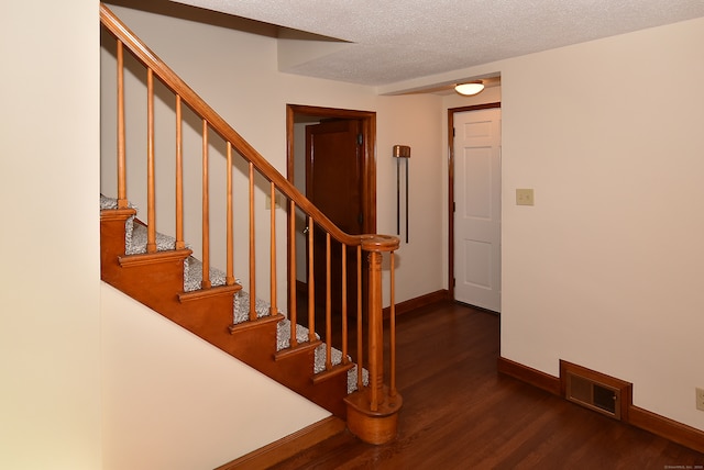 stairway featuring a textured ceiling and hardwood / wood-style flooring