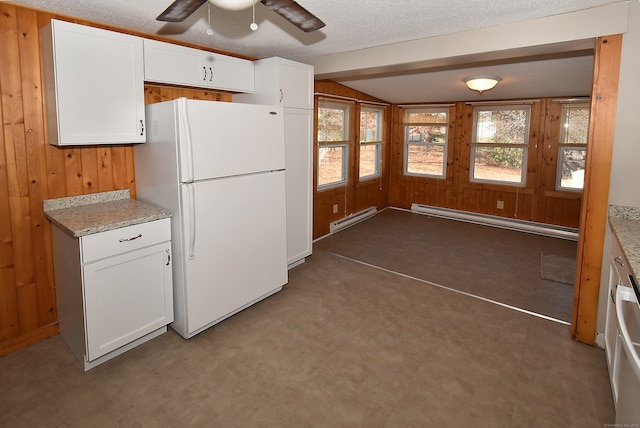 kitchen featuring white cabinets, white refrigerator, a baseboard radiator, and wood walls