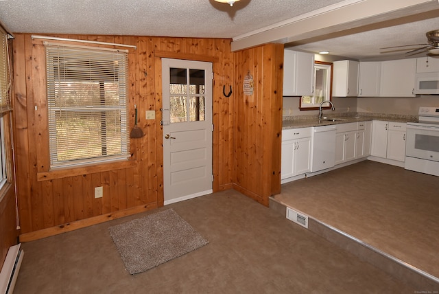 kitchen featuring sink, a baseboard heating unit, a textured ceiling, white appliances, and wooden walls