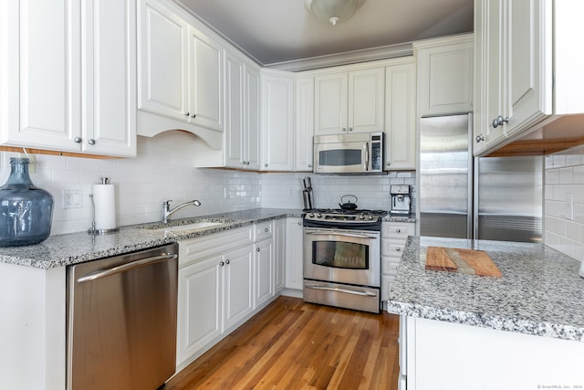 kitchen with backsplash, stainless steel appliances, sink, light hardwood / wood-style flooring, and white cabinetry