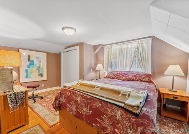 bedroom with a closet, light hardwood / wood-style flooring, and lofted ceiling