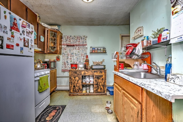 kitchen with a textured ceiling, ventilation hood, white appliances, and sink