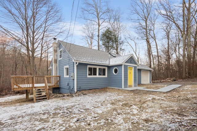 view of front of house featuring a garage, roof with shingles, a deck, and a chimney