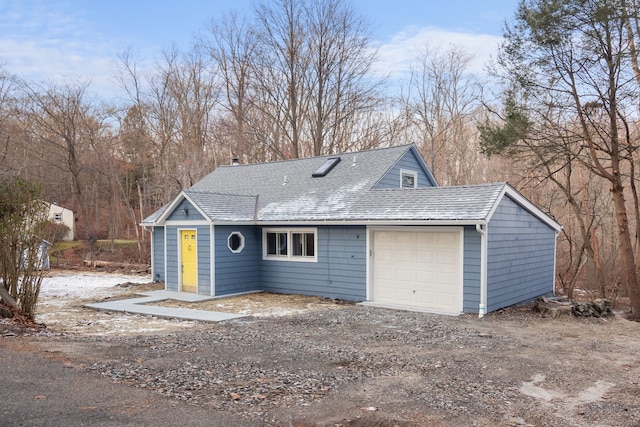 view of front of house with a garage, driveway, and a shingled roof