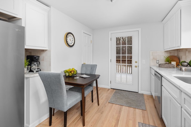 kitchen with white cabinetry, light wood-style floors, baseboards, and appliances with stainless steel finishes