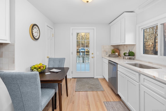 kitchen featuring baseboards, dishwasher, decorative backsplash, light wood-style flooring, and white cabinetry