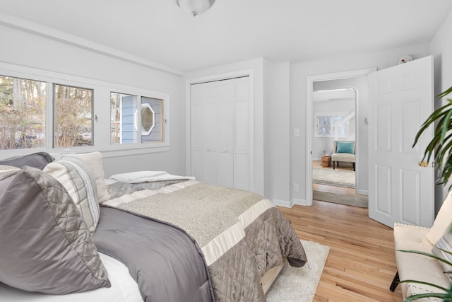 bedroom with light wood-style floors, a closet, and baseboards