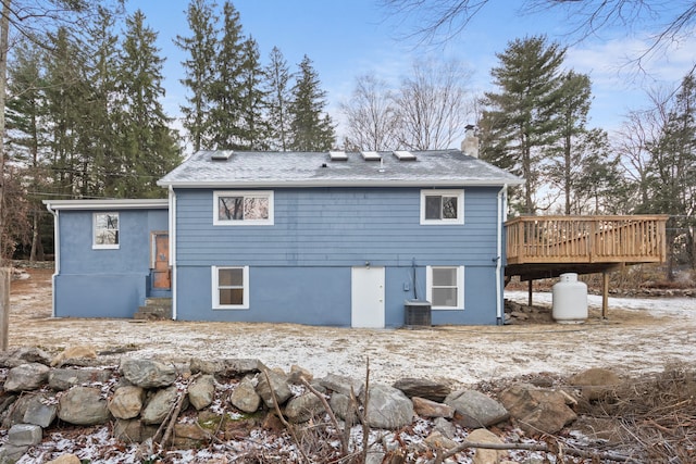 rear view of property featuring a shingled roof, central AC unit, a chimney, and a wooden deck