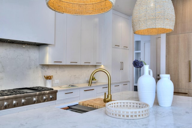 kitchen featuring white cabinetry, stainless steel gas cooktop, light stone counters, and decorative backsplash