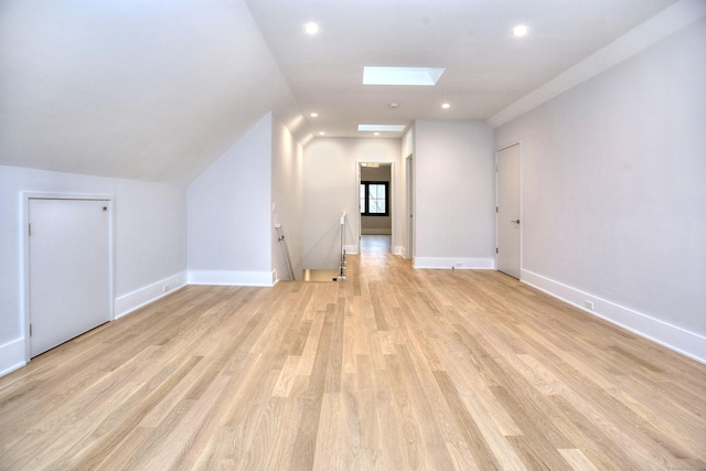 additional living space featuring light hardwood / wood-style flooring and vaulted ceiling with skylight