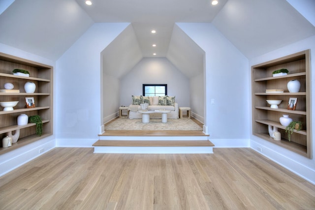 interior space featuring lofted ceiling, built in shelves, and light hardwood / wood-style flooring