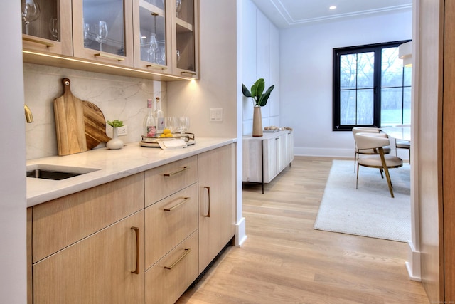 interior space featuring tasteful backsplash, light brown cabinetry, light stone countertops, and light wood-type flooring