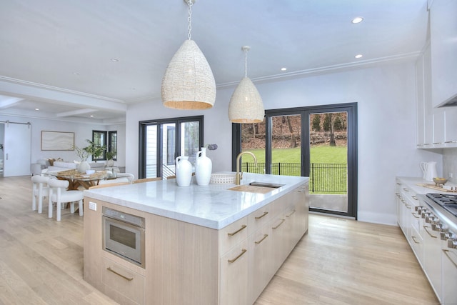 kitchen with pendant lighting, a kitchen island with sink, sink, and plenty of natural light