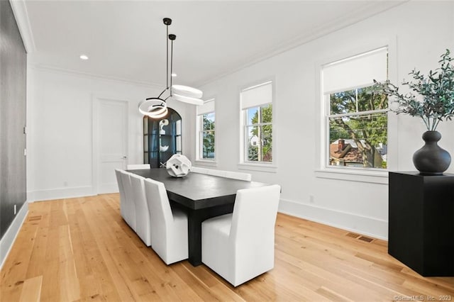 dining area with crown molding and light hardwood / wood-style flooring