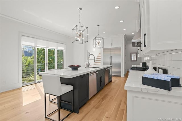 kitchen featuring white cabinetry, sink, a kitchen island with sink, decorative light fixtures, and stainless steel appliances