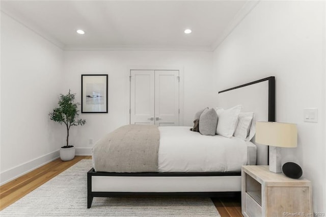 bedroom with crown molding, a closet, and wood-type flooring