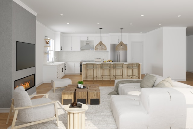 living room featuring sink, a large fireplace, light hardwood / wood-style floors, and ornamental molding