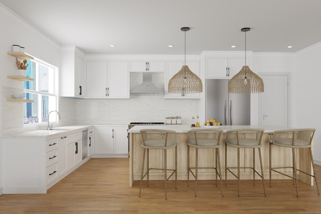 kitchen with wall chimney exhaust hood, pendant lighting, white cabinetry, built in refrigerator, and a kitchen island