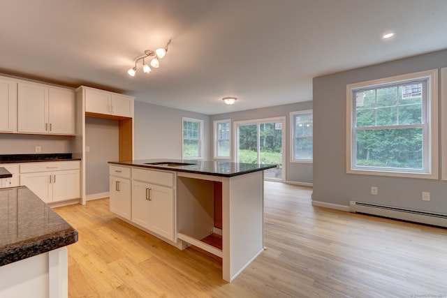 kitchen featuring white cabinets, a center island, a baseboard radiator, and light hardwood / wood-style flooring