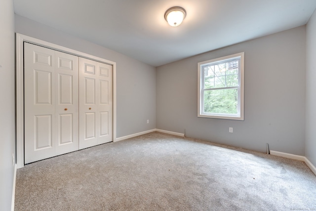 unfurnished bedroom featuring light carpet and a closet