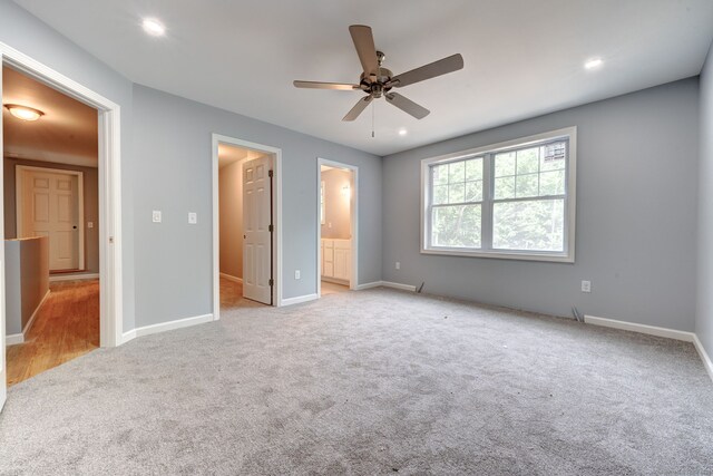 unfurnished bedroom with ensuite bathroom, ceiling fan, and light colored carpet