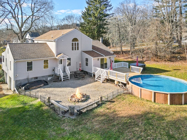 rear view of house featuring a swimming pool side deck, a yard, and a fire pit