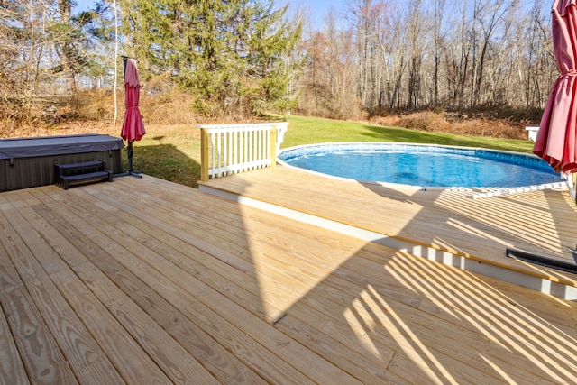 view of swimming pool featuring a lawn, a deck, and a hot tub