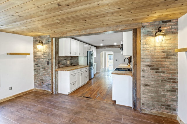 kitchen with appliances with stainless steel finishes, wood ceiling, hardwood / wood-style flooring, white cabinets, and butcher block countertops