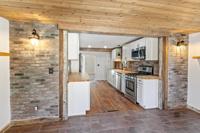 kitchen with white cabinets, butcher block countertops, dark hardwood / wood-style flooring, and appliances with stainless steel finishes