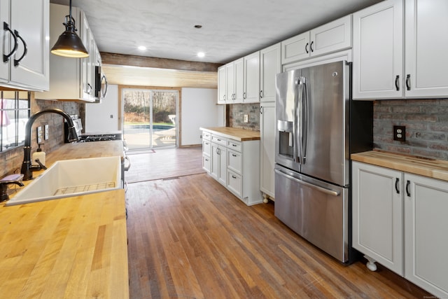 kitchen featuring wood counters, appliances with stainless steel finishes, pendant lighting, hardwood / wood-style floors, and white cabinetry