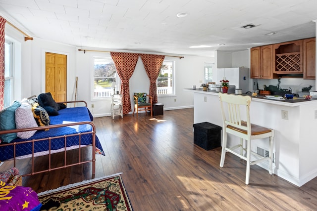 kitchen with kitchen peninsula, a breakfast bar, white fridge, and dark hardwood / wood-style floors