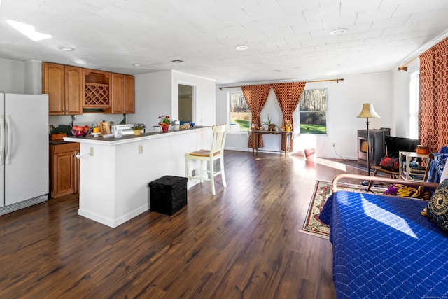 kitchen with a breakfast bar area, kitchen peninsula, white fridge, and dark wood-type flooring