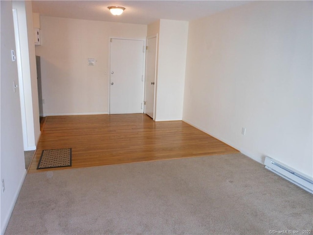 empty room featuring light carpet and a baseboard heating unit