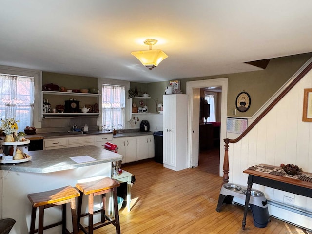 kitchen featuring white cabinetry, wood walls, and light wood-type flooring