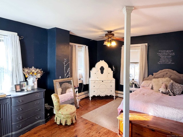 bedroom featuring a baseboard radiator, ceiling fan, wood-type flooring, and decorative columns