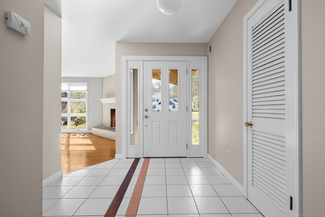 entryway with a brick fireplace and light tile patterned flooring