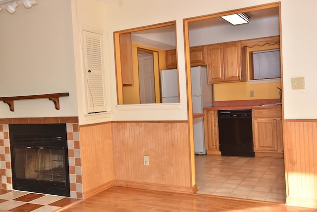 kitchen featuring a tile fireplace, sink, white refrigerator, and black dishwasher