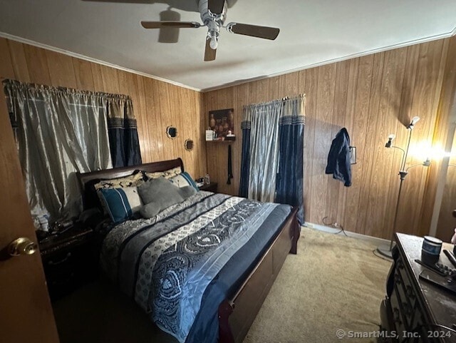 bedroom with ceiling fan, crown molding, light carpet, and wood walls