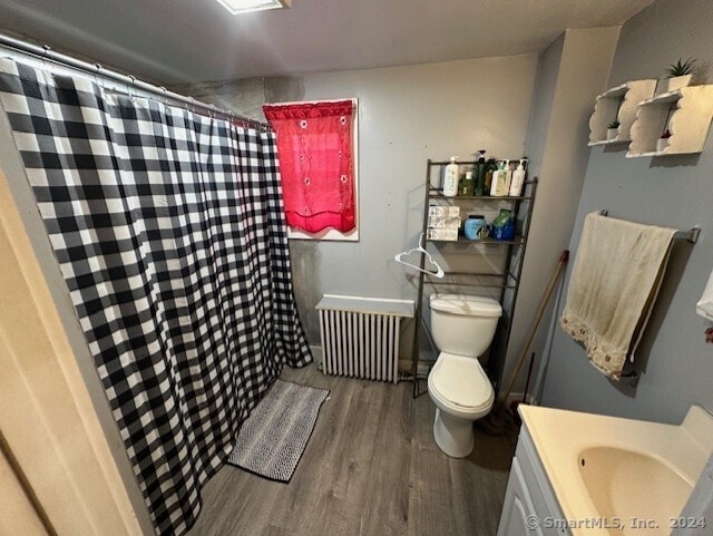 bathroom with vanity, toilet, wood-type flooring, and radiator