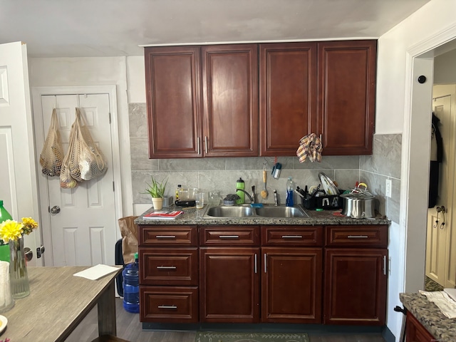 kitchen featuring decorative backsplash, dark stone counters, and sink