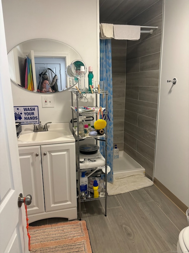 bathroom featuring hardwood / wood-style floors, vanity, and a tile shower