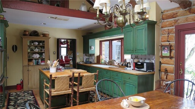 87 Red Coat Rd, Westport, CT 06880 - kitchen with green cabinets, stainless steel microwave, a chandelier, and butcher block counters