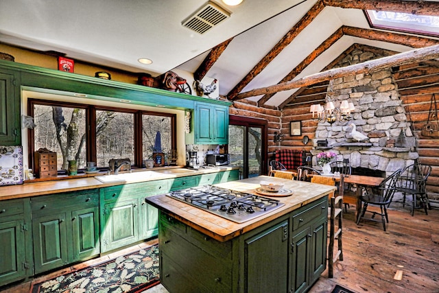 87 Red Coat Rd, Westport, CT 06880 - kitchen with green cabinetry, wood counters, log walls, stainless steel gas stovetop, and hardwood / wood-style floors
