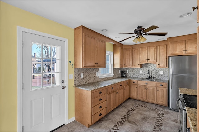 kitchen with light tile patterned flooring, sink, stainless steel refrigerator, ceiling fan, and stove