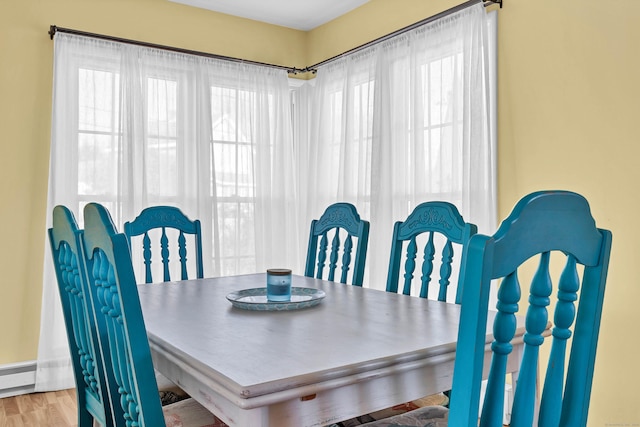 dining space with baseboard heating and light hardwood / wood-style floors