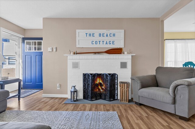 living room with a brick fireplace and hardwood / wood-style floors