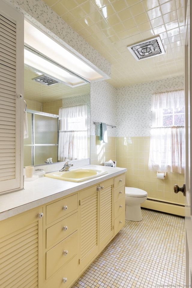 bathroom with vanity, baseboard heating, tile patterned flooring, toilet, and a shower with shower door